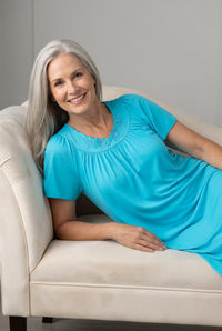 Woman in a Petals Flutter Sleeve nightgown relaxing on a beige couch 