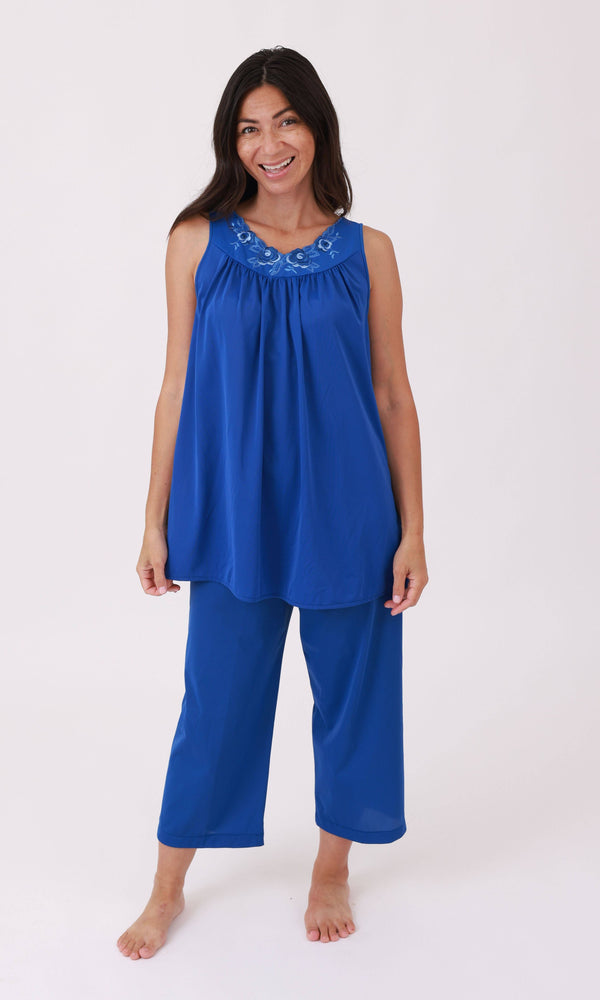 Woman wearing a blue sleeveless top and pants on a white background